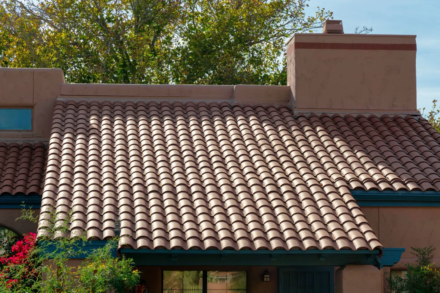 A red clay tile roof on a stucco desert-style home under a clear sky