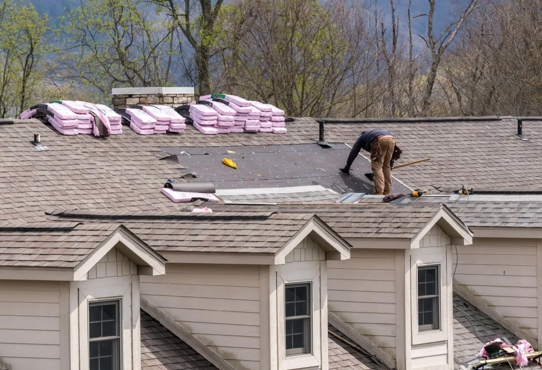 A roofer removing old shingles before installing a new asphalt shingle roof