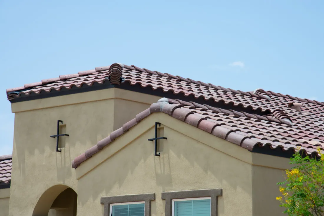 A red clay tile roof on a stucco desert-style home in the sun